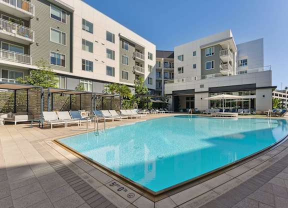 A large swimming pool in front of a building with a white and grey exterior.
