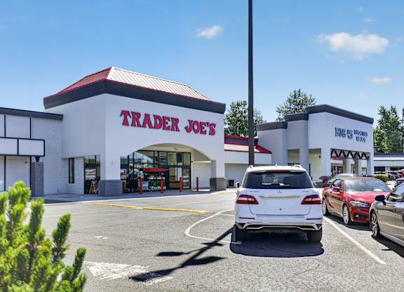 A white car is parked in front of a Trader Joe's store.