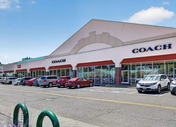 A Coach store with cars parked in front.