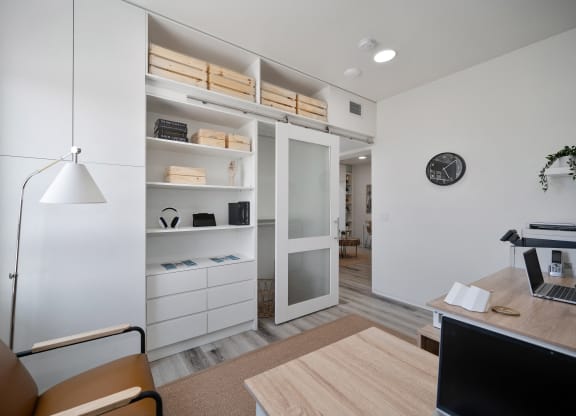 a home office with a desk and a closet with shelves