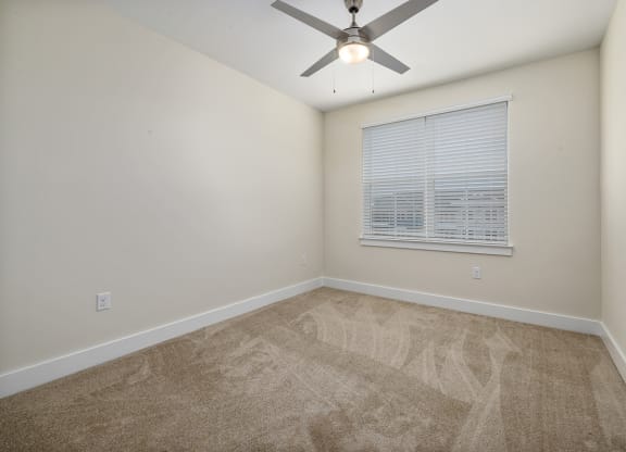 Carpeted bedroom with a ceiling fan and light with picture window
