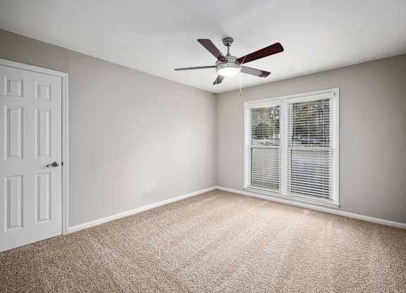 A room with a ceiling fan and a window with blinds.