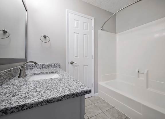 A bathroom with a granite countertop and white fixtures.