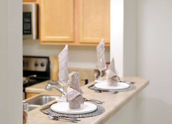 a kitchen with a sink and a counter top with plates and napkins on it