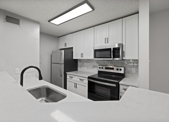a kitchen with white cabinets and black appliances and a sink