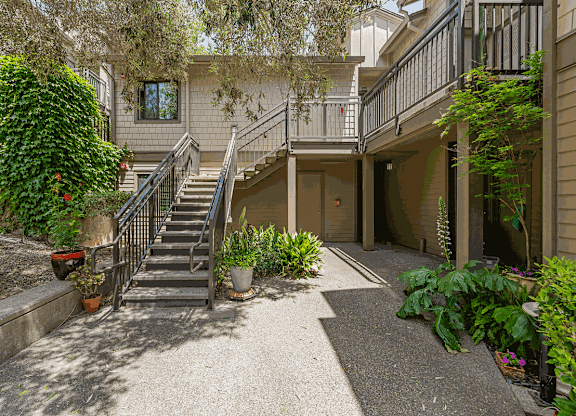 the entrance to a house with stairs and a yard with plants