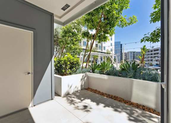 A white door is open to a balcony with a view of a cityscape.