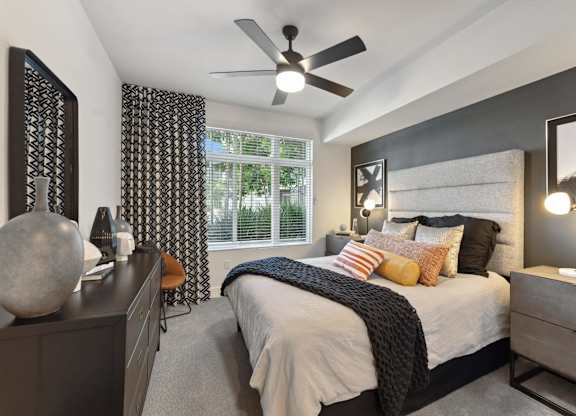 A bedroom with a bed, nightstand, and a ceiling fan.