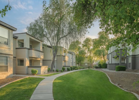 an exterior view of an apartment complex with green grass and trees