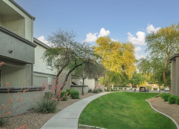 a walkway between two apartment buildings with grass and trees