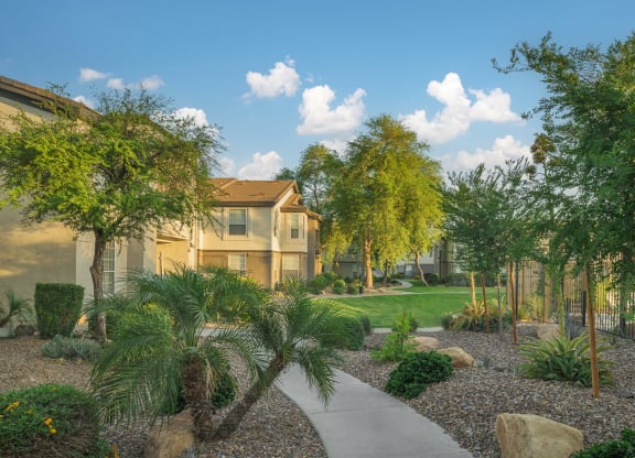 a courtyard with trees and a sidewalk in front of a building