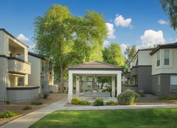 a gazebo sits in the middle of a yard in front of apartments