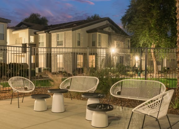 a patio with chairs and tables in front of an apartment building