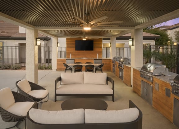 a patio with couches and chairs and a grill and a television