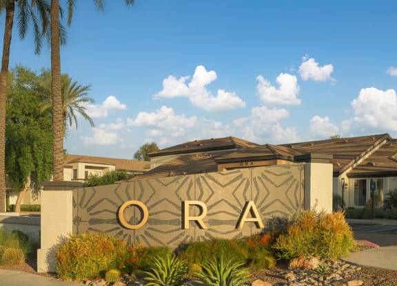a sign that says in front of a building with palm trees