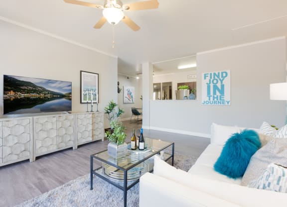 a living room with white furniture and a ceiling fan