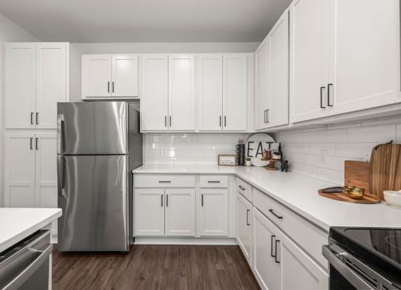 a kitchen with white cabinets and a stainless steel refrigerator