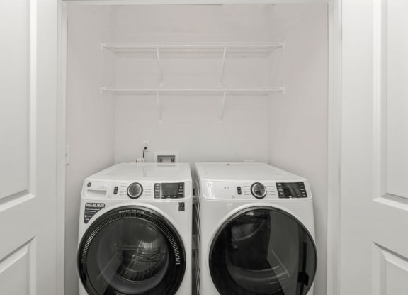a white washer and dryer in a white closet