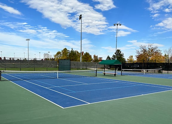 A tennis court with a net and two light poles.