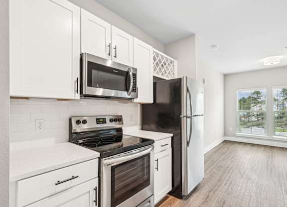 a kitchen with white cabinets and stainless steel appliances