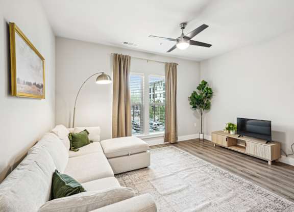 a living room with a white couch and a ceiling fan