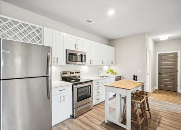 a white kitchen with stainless steel appliances and a wooden table