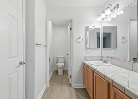 A white bathroom with a toilet, sink, and mirror.