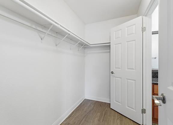 A spacious closet with a shelf and wood floors.