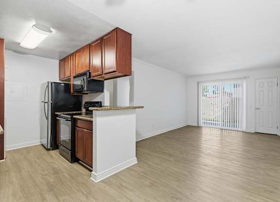 A modern kitchen with a black fridge and microwave, and brown cabinets.