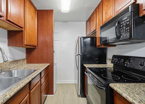 A kitchen with black appliances and wooden cabinets.