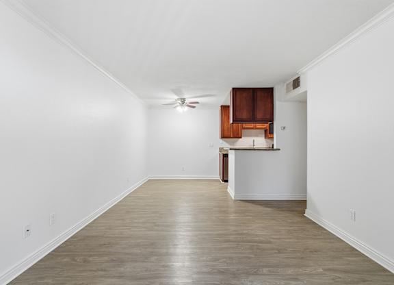 A living room and dining room with wooden floors and a ceiling fan.