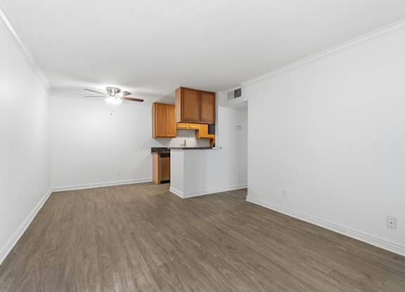 A spacious living room and dining room with wood floors, and a ceiling fan.