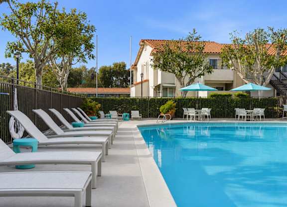 A resort style swimming pool with lounge chairs and umbrellas.