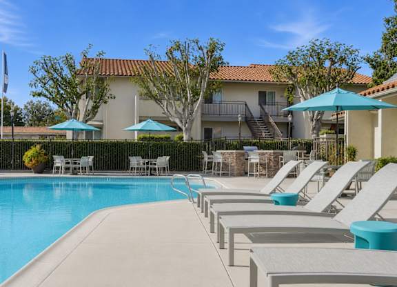 A resort style swimming pool with lounge chairs and umbrellas.