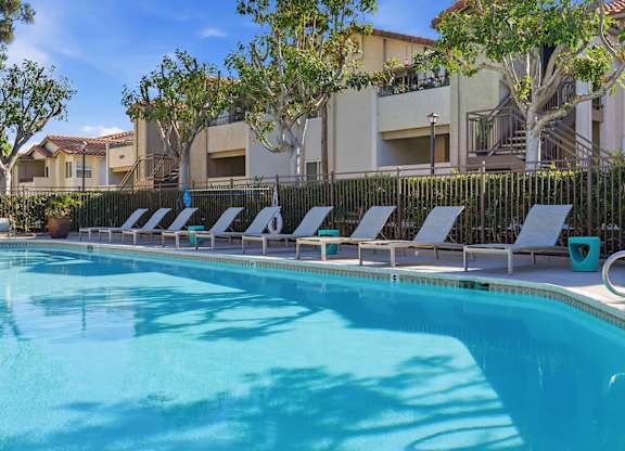 A resort style swimming pool with lounge chairs and umbrellas.
