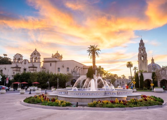 a fountain in the middle of a city square at sunset