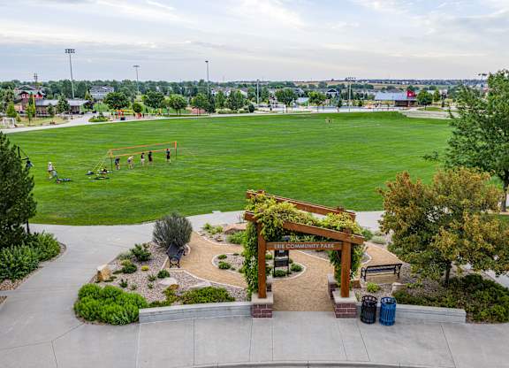 A park with a green field and a wooden archway.