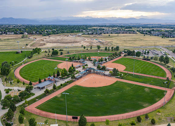 A large, open athletic track with a red track surface and a green grass field surrounding it.