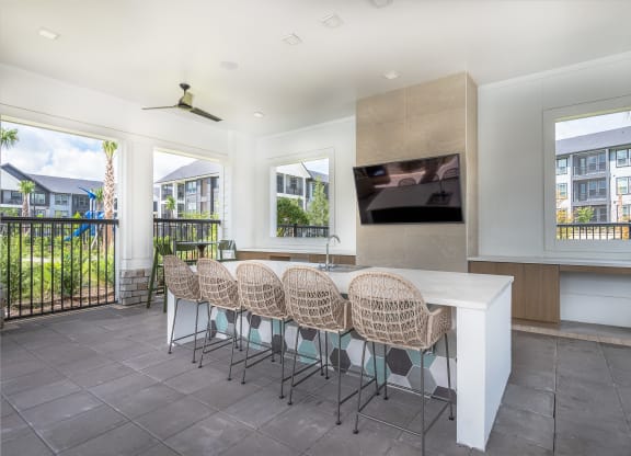 a kitchen with a bar and chairs and a television