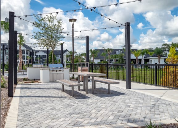 an outdoor patio with picnic tables and a grill