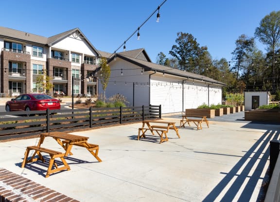 a patio with wooden benches and tables in front of a building