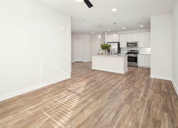 an open kitchen and living room with white walls and wood flooring