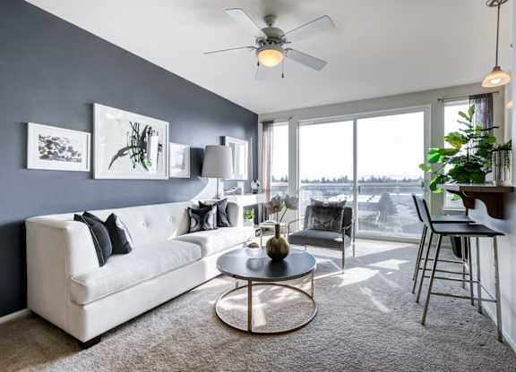 a living room with a large window and a ceiling fan