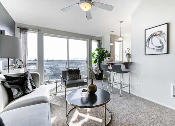 a living room with a large window and a ceiling fan