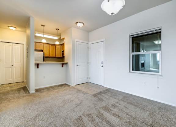 a bedroom with a large window and a door leading to a kitchen