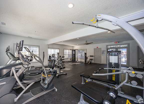 A gym with a variety of equipment including treadmills, weights, and exercise machines.