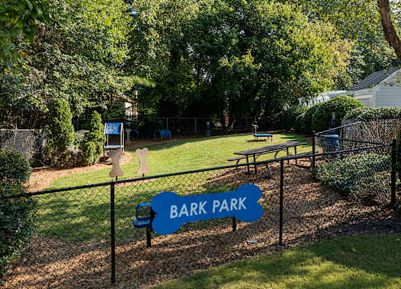 A sign that says Bark Park is in front of a fence.