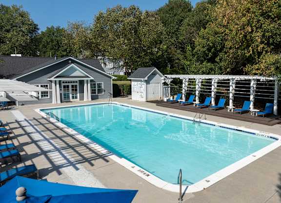 A swimming pool surrounded by trees and a small building.