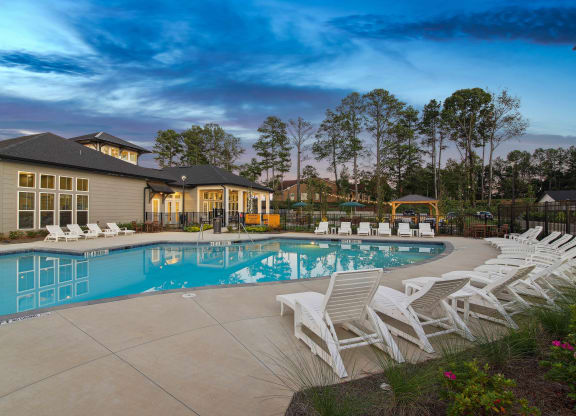 a swimming pool with chairs and a building in the background
