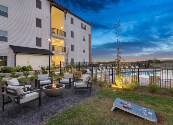 an outdoor patio with chairs and a fire pit next to a pool